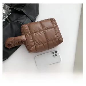 Brown quilted puffer tote bag shown next to a smartphone for size reference and scale