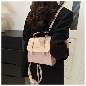 Detail of pink faux leather handbag featuring gold buckles and adjustable shoulder strap