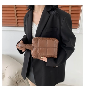 Detail of coffee brown quilted puffer clutch featuring square patterns and side strap