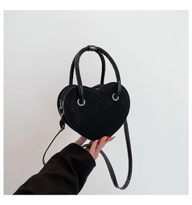 Dettaglio della borsa a forma di cuore con strass neri e bordi in vernice nera lucida