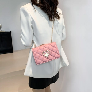 Pink quilted crossbody bag with golden heart buckle and chain strap shown on model