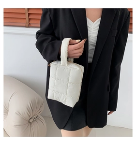 Close-up of white quilted mini bag with gold zipper and nylon grid texture details