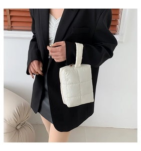 Close-up of a white quilted down-style handbag with a soft puffy texture and top handle