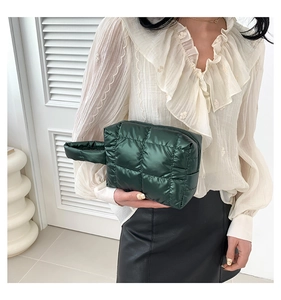 Close-up of dark green quilted puffer nylon cosmetic bag with elegant stitching