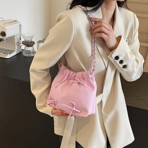 Sac seau rose en nylon avec nœuds et bandoulière chaîne argentée porté par un mannequin