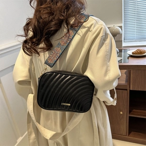 Fashionable black quilted crossbody bag with stylish patterned strap and gold hardware