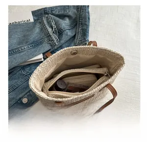 Vue détaillée de dessus d'un grand sac cabas en paille avec poignées en cuir et pochette