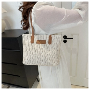 Gros plan d'un grand sac cabas en paille tressée avec anses et patch en cuir marron