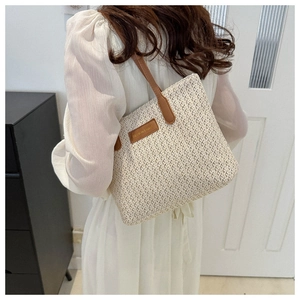 Détail de l'étiquette en cuir et des coutures sur un grand sac cabas en paille d'été