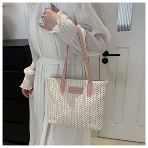 Détail d'un grand cabas en paille avec poignée en cuir rose et écusson de mode