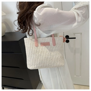 Détail de la poignée en cuir rose et de la texture tissée d'un grand sac cabas en paille
