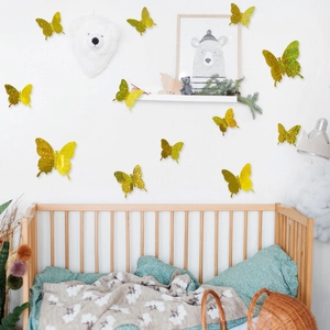 Golden 3D glitter butterfly wall decals decorating a cozy nursery wall above a baby crib