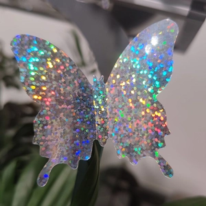 Macro shot of 3D holographic butterfly wall stickers with glitter finish on green leaves