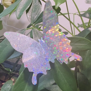 Macro detail of 3D holographic butterfly wall sticker with glitter on green leaves