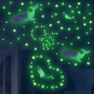 Luminous wall sticker detail showing green glowing whales and stars in a dark nursery room