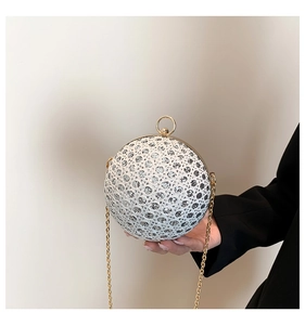 Detail of spherical evening clutch with silver sequins and gold ring handle closure