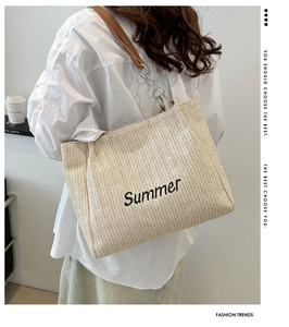 Detailed macro view of woven straw texture and Summer embroidery on a beige tote bag