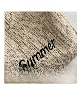 Detail view of beige woven tote bag featuring black Summer embroidery and fine fiber texture