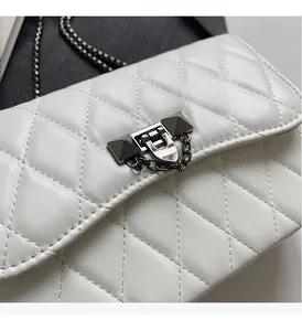 Close-up of quilted white leather bag featuring gunmetal rivet lock and chain detail