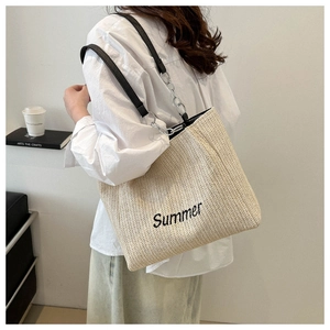 Straw tote bag with Summer embroidery and chain strap shown on model shoulder