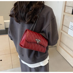 Close-up of red quilted leather bag with elegant metal chain strap and geometric clasp