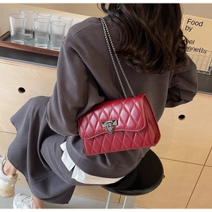 Detailed view of the red quilted chain bag with silver clasp and metallic strap