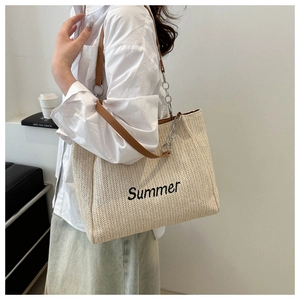 Detail of summer straw tote with black Summer embroidery and leather chain strap