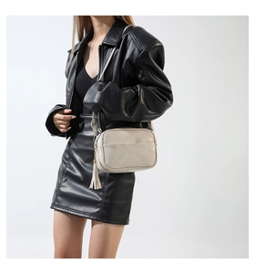 Detail of cream white crossbody camera bag with V-quilted stitching and long side tassel