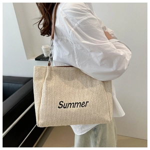Detail of large straw tote bag with black Summer embroidery and leather chain strap