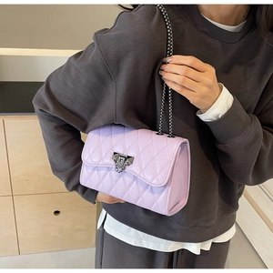 Close-up of lavender quilted leather bag with metallic chain and triangular stud clasp