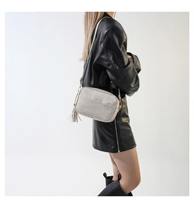 Close-up of elegant quilted crossbody bag with gold hardware and tassel detail on model