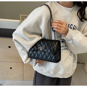 Close-up of black quilted chain shoulder bag with metallic twist lock and glossy texture