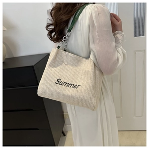 Detail of straw tote with Summer embroidery and green leather metal chain strap