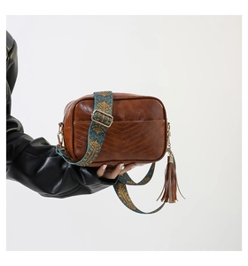 Detail of vintage brown shoulder bag with ethnic woven strap and decorative side tassel