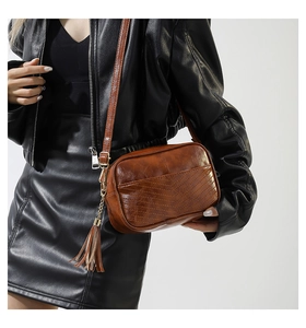 Detailed close-up of brown PU leather crossbody bag featuring V-quilted texture and tassel