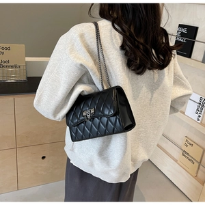 Chic black quilted shoulder bag with silver chain strap and metal lock in lifestyle setting