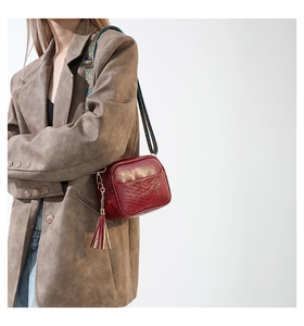 Detail of dark red PU leather bag with V-shaped quilting and ethnic patterned strap