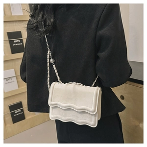 Detail of off-white crossbody bag with wavy flap design and metal ball chain strap