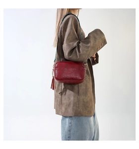 Detail of burgundy PU leather crossbody bag with V-stitched texture and woven strap