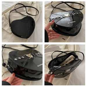 Détail du sac cœur en cuir verni noir avec clous argentés et espace de rangement interne
