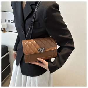 Detail of a brown quilted leather crossbody bag with chain strap and metal lock buckle