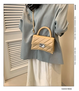 Sac à bandoulière crème minimaliste avec fond incurvé porté par un mannequin