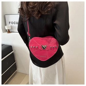Détail du sac à main rose en forme de cœur en cuir verni avec clous argentés et boucle métal