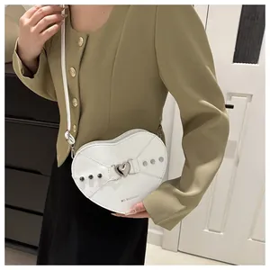 Gros plan sur le sac en cuir verni blanc en forme de cœur avec boucle et clous argentés