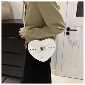 Détail du sac à bandoulière blanc en forme de cœur avec rivets argentés et boucle en métal