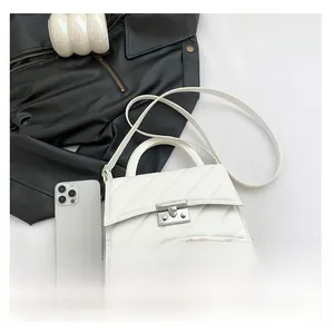 Détail du sac bandoulière blanc matelassé avec texture en V et fermoir rotatif argenté