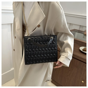 Close-up of black matelassé quilted handbag with elegant gold chain strap detail