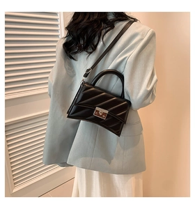Détail d'un sac à main noir matelassé avec fermoir argenté porté par un mannequin