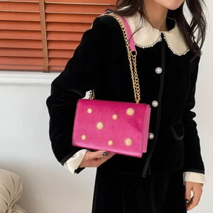 Fuchsia velvet shoulder bag with gold star studs and chain strap worn by model