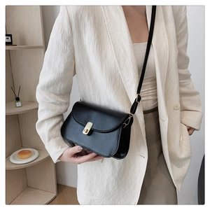 Détail d'un sac bandoulière en cuir noir minimaliste avec boucle en métal doré chic